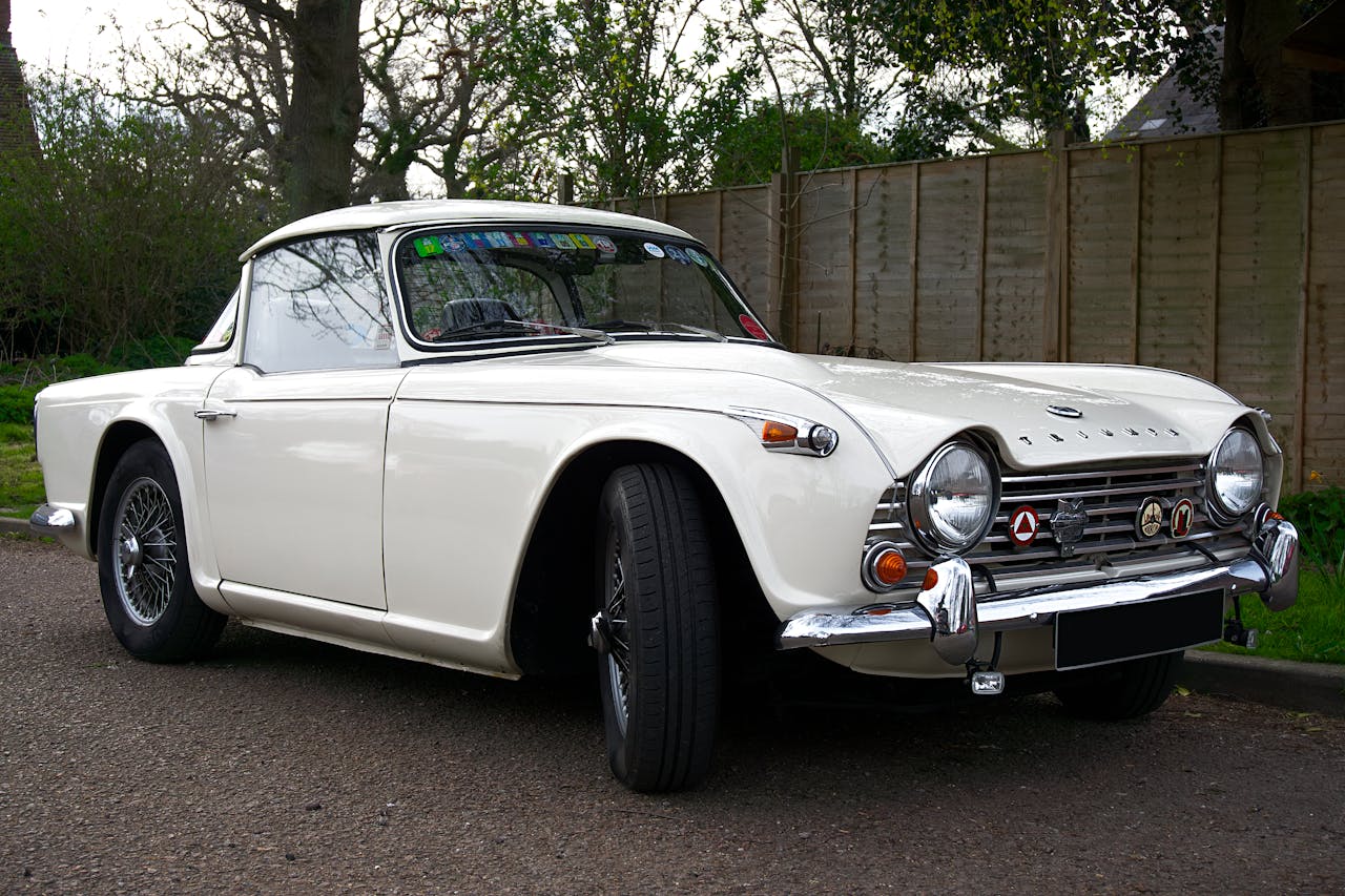 Elegant white Triumph sports car showcased outdoors, embodying vintage automotive style.