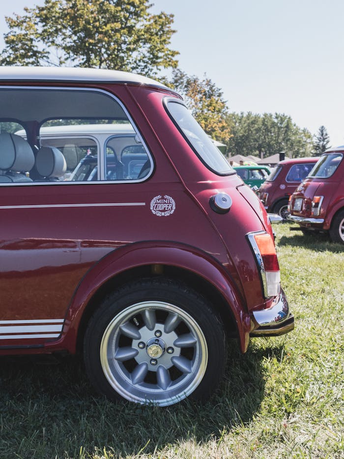 Side view of a classic red Mini Cooper displayed at an outdoor car show in Oakville, Canada.